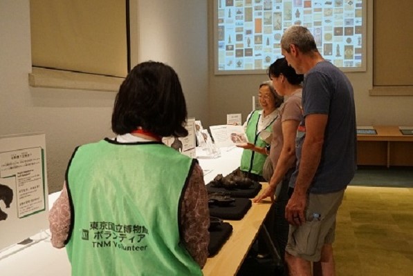 本館19室で土偶のハンズオンツールをご案内するボランティアのイメージ画像